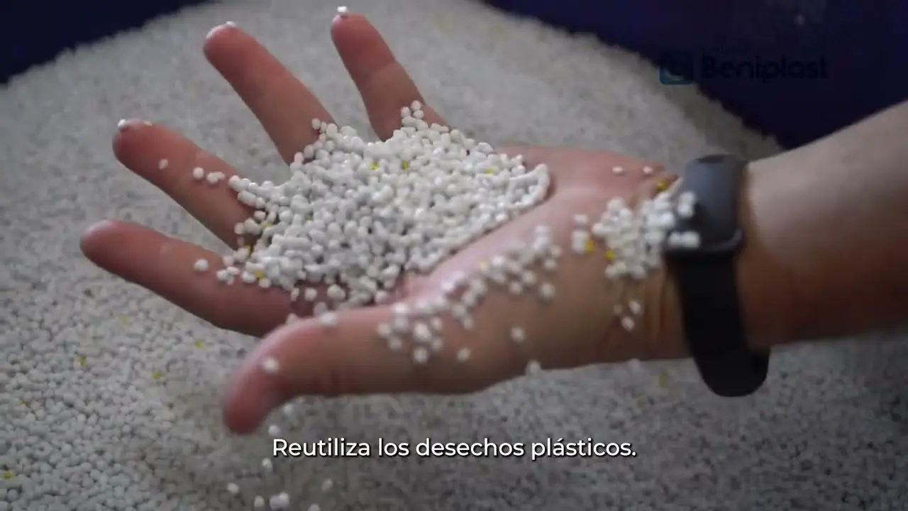 Mano sosteniendo pellets de plástico reciclado